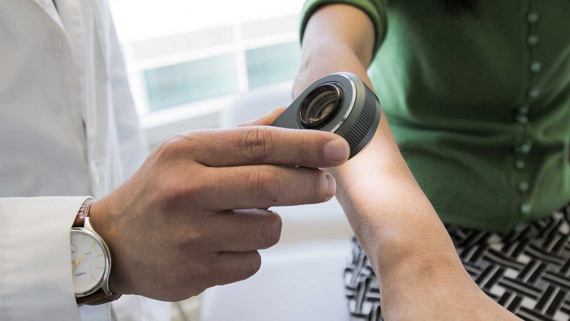 A dermatologist uses a dermatoscope, a type of handheld microscope, to look at skin. Computer scientists at Stanford have created an artificially intelligent diagnosis algorithm for skin cancer that matched the performance of board-certified dermatologists. 