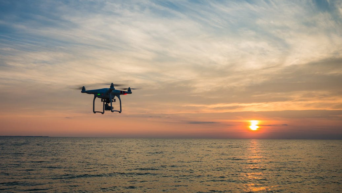 Black Quadcopter Drone Flying on the Sea Shore Under Blue and White Sky during Sun Set 