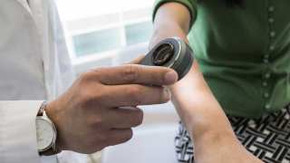 A dermatologist uses a dermatoscope, a type of handheld microscope, to look at skin. Computer scientists at Stanford have created an artificially intelligent diagnosis algorithm for skin cancer that matched the performance of board-certified dermatologists. 